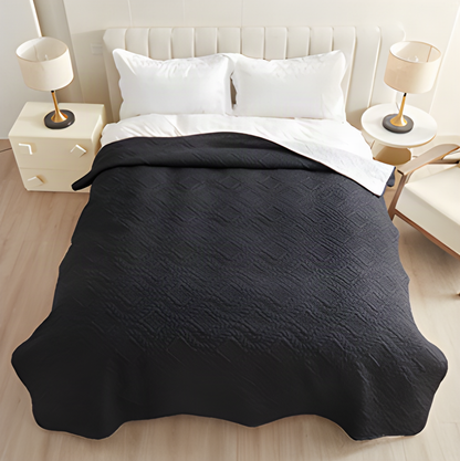 Black waterproof quilted dog blanket spread over a bed
