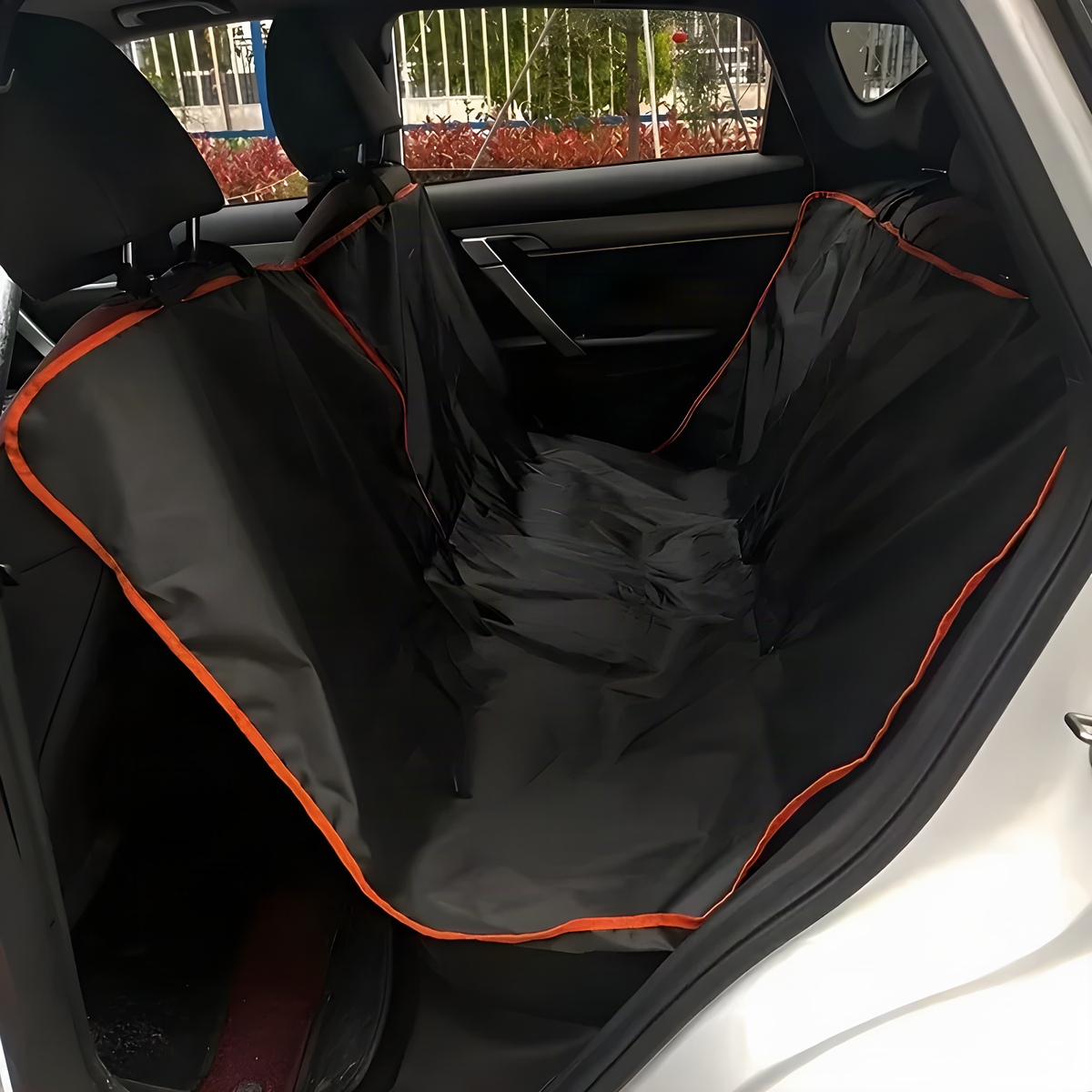 Black Oxford dog car hammock with orange trim fitted across a back seat, front view